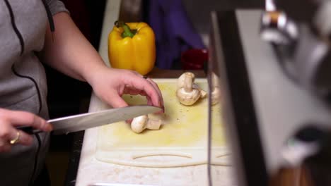 una vista lateral de cortar champiñones portabella por la mitad en la parte superior del mostrador de la cocina