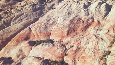 flyover aerial view of orange and white striped mountains in yant flats, utah near st