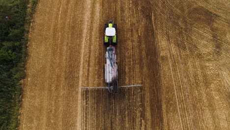 Cinematic-tilt-down-camera-following-green-yellow-tractor-harvester-driver-machine-plowing-field-crops-vegetable-vegan-alternative-drone-aerial-farmer-agro-dirt-animals-cattle-cow-collecting-food-seed