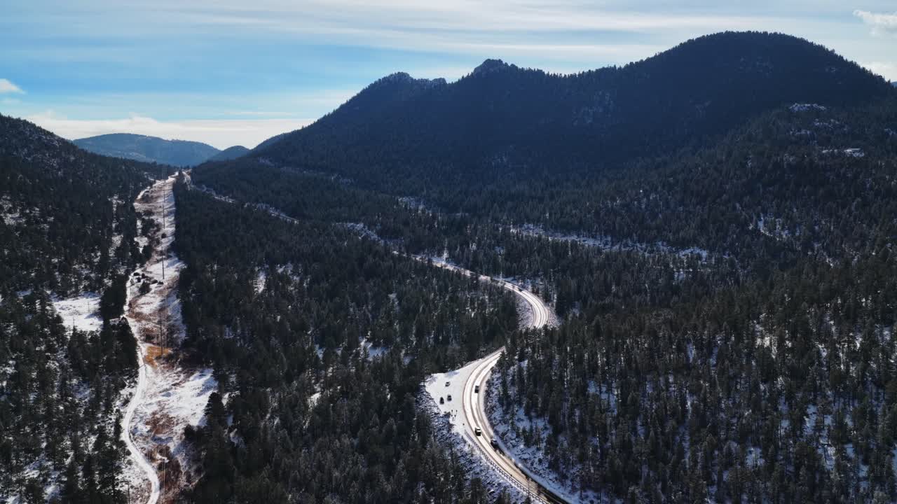 Estes Park Portskilt. Estes Park Landevej 36 Colorado. Dronebillede vinter, solrig blå himmel morgen, frisk sne. Park Hill, Mummy Range, Panorama Peak. Biler, trafik. Iset, blæsende vej. Larimer County. Fremad.