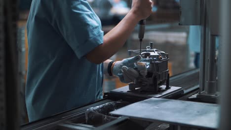 industrial worker assembling metal appliances at automatical conveyor at factory