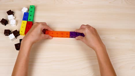 manos montando cubos coloridos en una mesa de madera