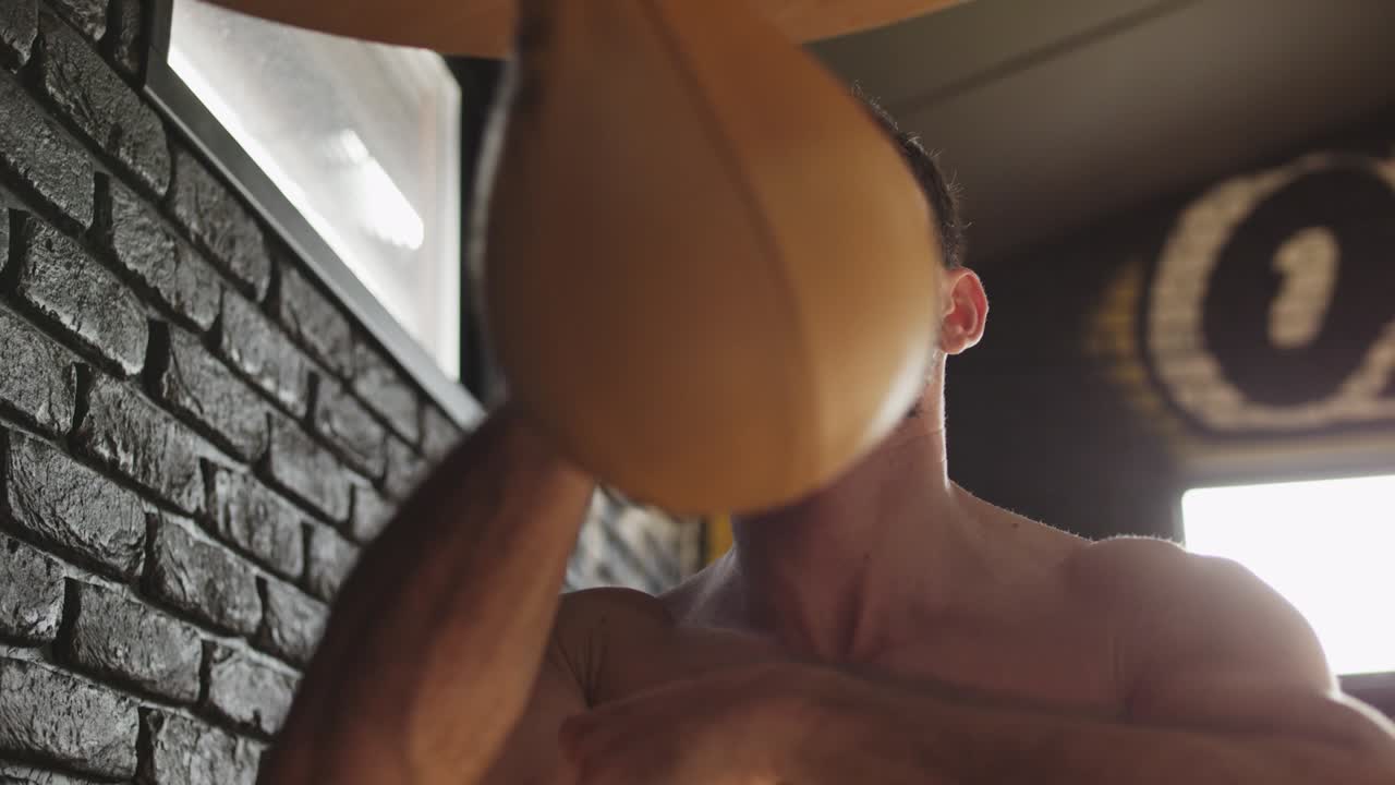 검은 수염을 가진 예쁜 권투 선수가 체육관에서 스피드백으로 운동하고 있습니다. 열심히 일하고 있습니다.