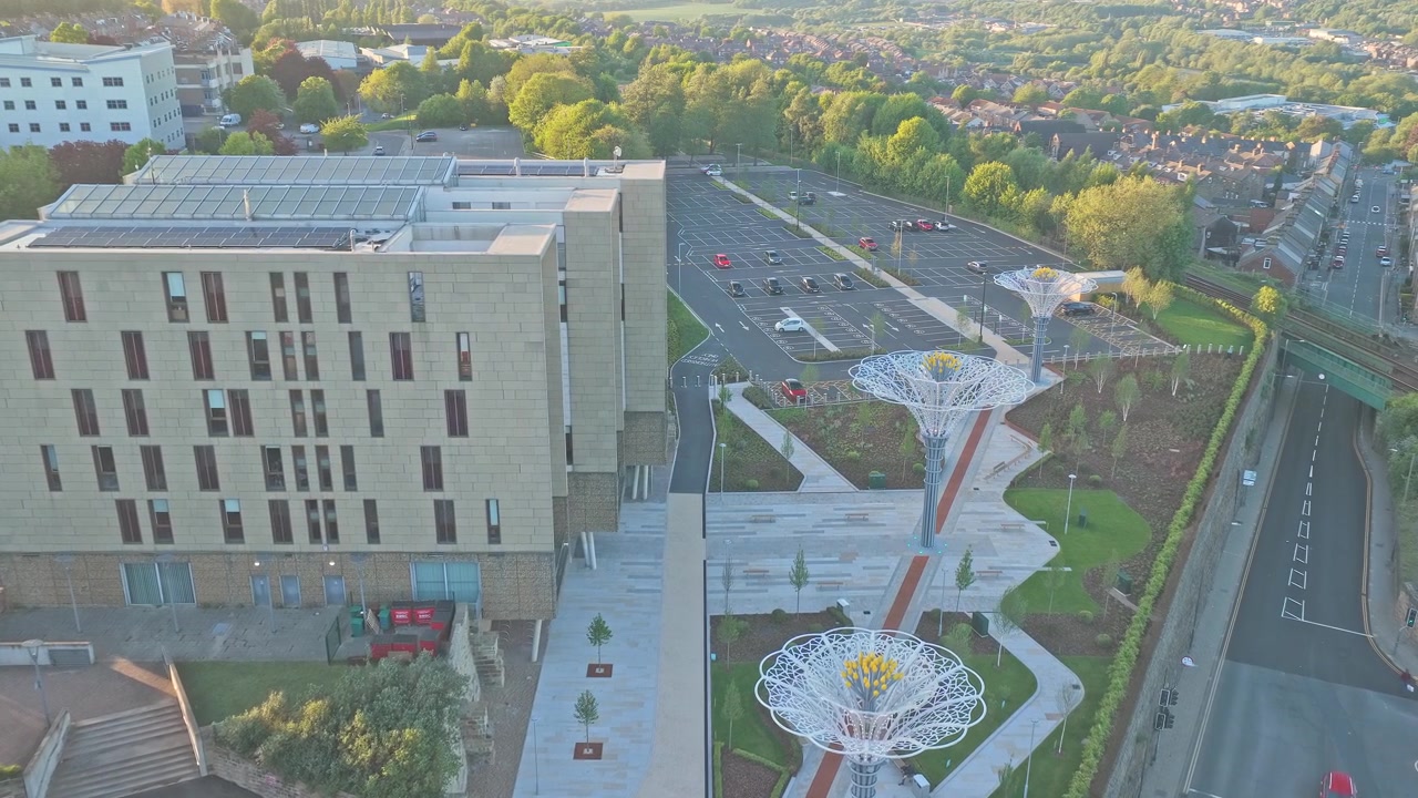 Digital Media Centre und umliegende Stadtlandschaft in Barnsley, South Yorkshire, England, bei Sonnenuntergang mit beleuchteter Rosen-Überdachungsinstallation und abendlicher Stadtatmosphäre, Luftabstieg.