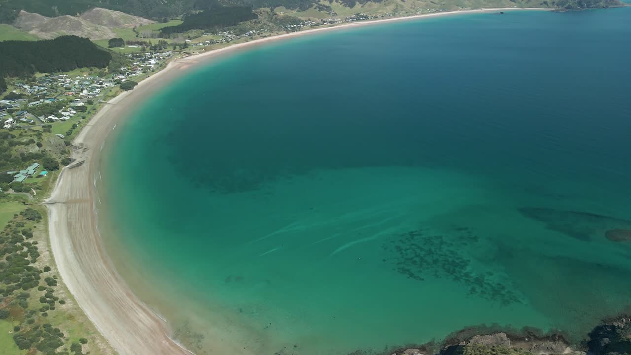 drone elevándose sobre la bahía de opito en la impresionante península de coromandel