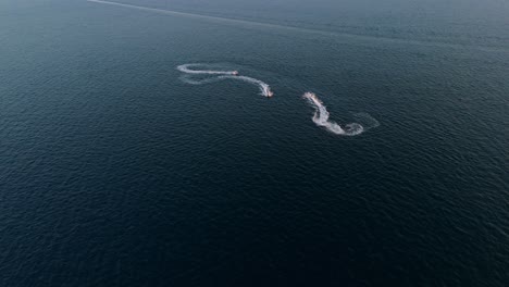 a speedboat creates swirling patterns on the calm blue waters near saranda, albania at sunset