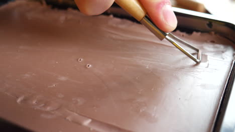 un artista y escultor tallando arcilla de modelado marrón de un bloque grande con una herramienta manual en un afeitado satisfactorio para comenzar a esculpir su proyecto de arte en un estudio