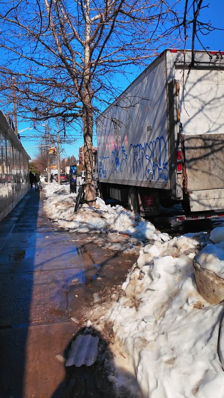 New York, USA, 9. februar 2026: Varebil og sykkel i snødekt bygate etter storm. Bakfra av en hvit lastebil parkert nær store hauger med skitten snø og et sykkelhjul i forgrunnen