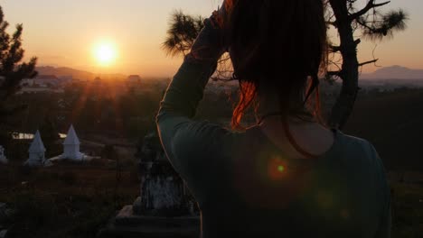 a female tourist enjoying and admiring the beautiful sunset over the phonsavan village in laos - wide shot