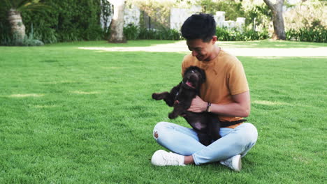 asian man playing with dog on grass, enjoying sunny day outdoors, in park, copy space