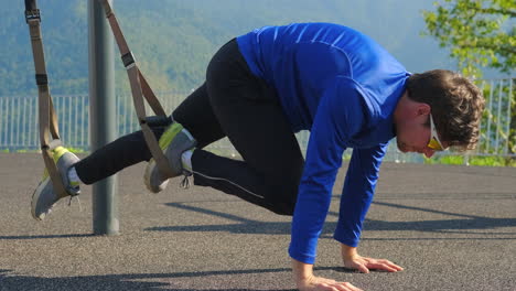 man performing suspension workout outside