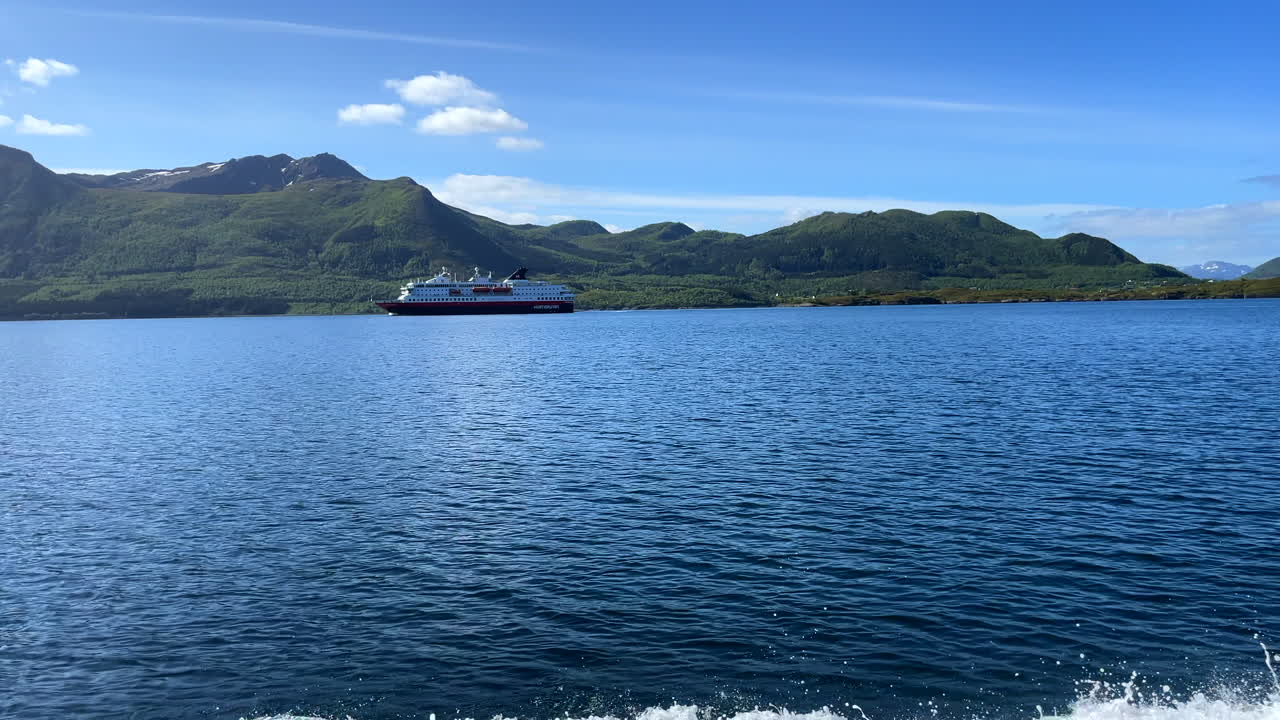 Panning shot from a cruising boat with a stunning landscape and a passing ferry inside Norwegian fjords along the coast