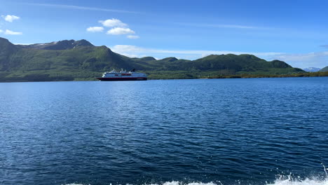 panning shot from a cruising boat with a stunning landscape and a passing ferry inside norwegian fjords along the coast