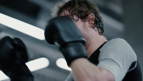 eager kickboxer training blows at gym. sportsman exercising in sport club