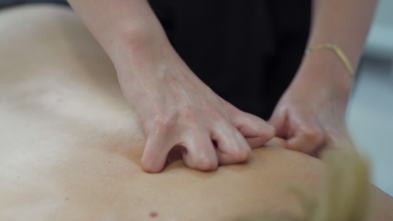 Hands of masseur performing a relaxing massage on the patient's back
