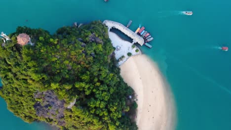 Ha-Long-Bay-Destino-De-Vacaciones-De-Viaje-De-Vietnam,-Antena-De-Arriba-Hacia-Abajo-De-Un-Pequeño-Islote-Con-Una-Playa-De-Arena-Tropical-Celestial-Y-Un-Barco-Amarrado-En-El-Muelle