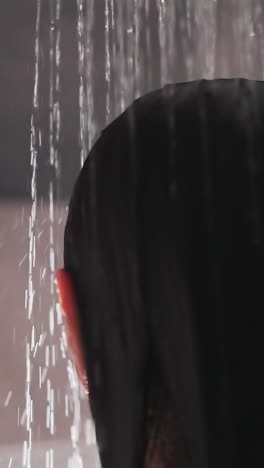 lady stands under flow of water in shower. woman with brunette hair stands in shower beginning to wash hair. morning routine for woman loves shower