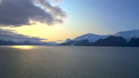 drone rising up and showing the sun and mountains at sunrise along the seward highway