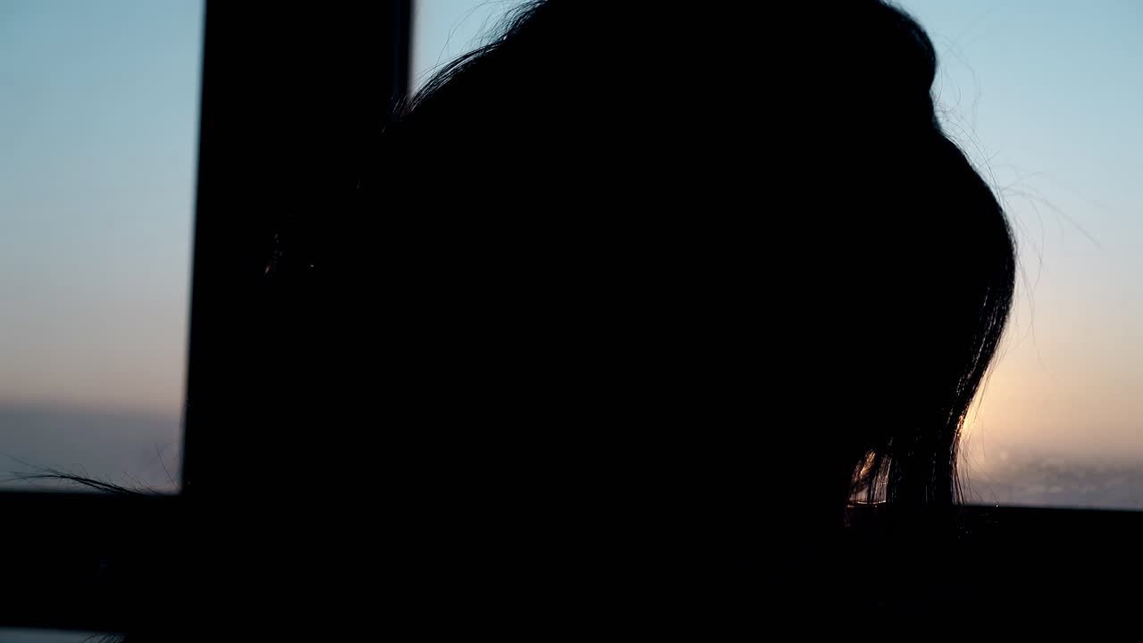 오렌지색 일몰에 곱슬머리를 가진 소녀의 가까운 실루 ⁇