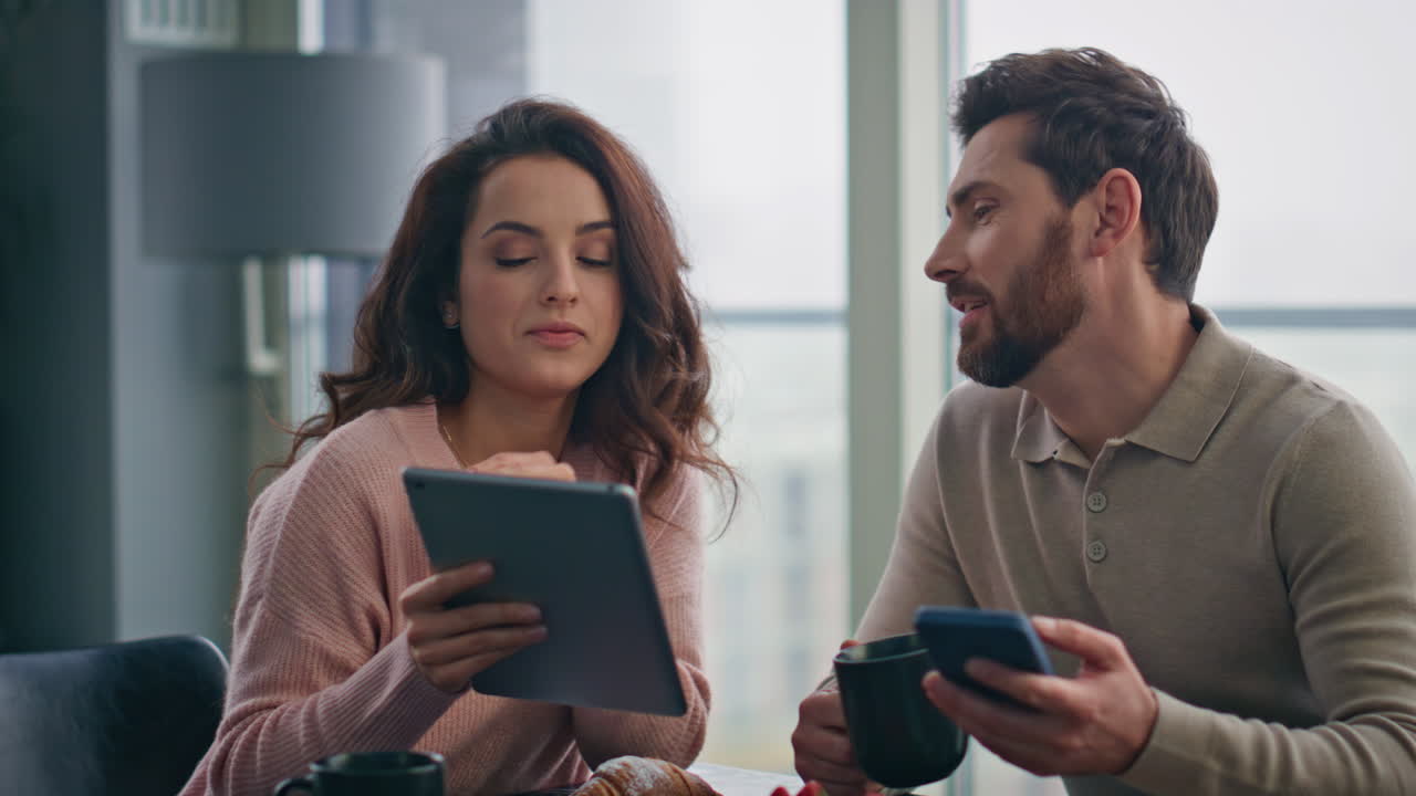 amantes felices discutiendo la pantalla de la tableta en el desayuno de fin de semana. hombre bebiendo