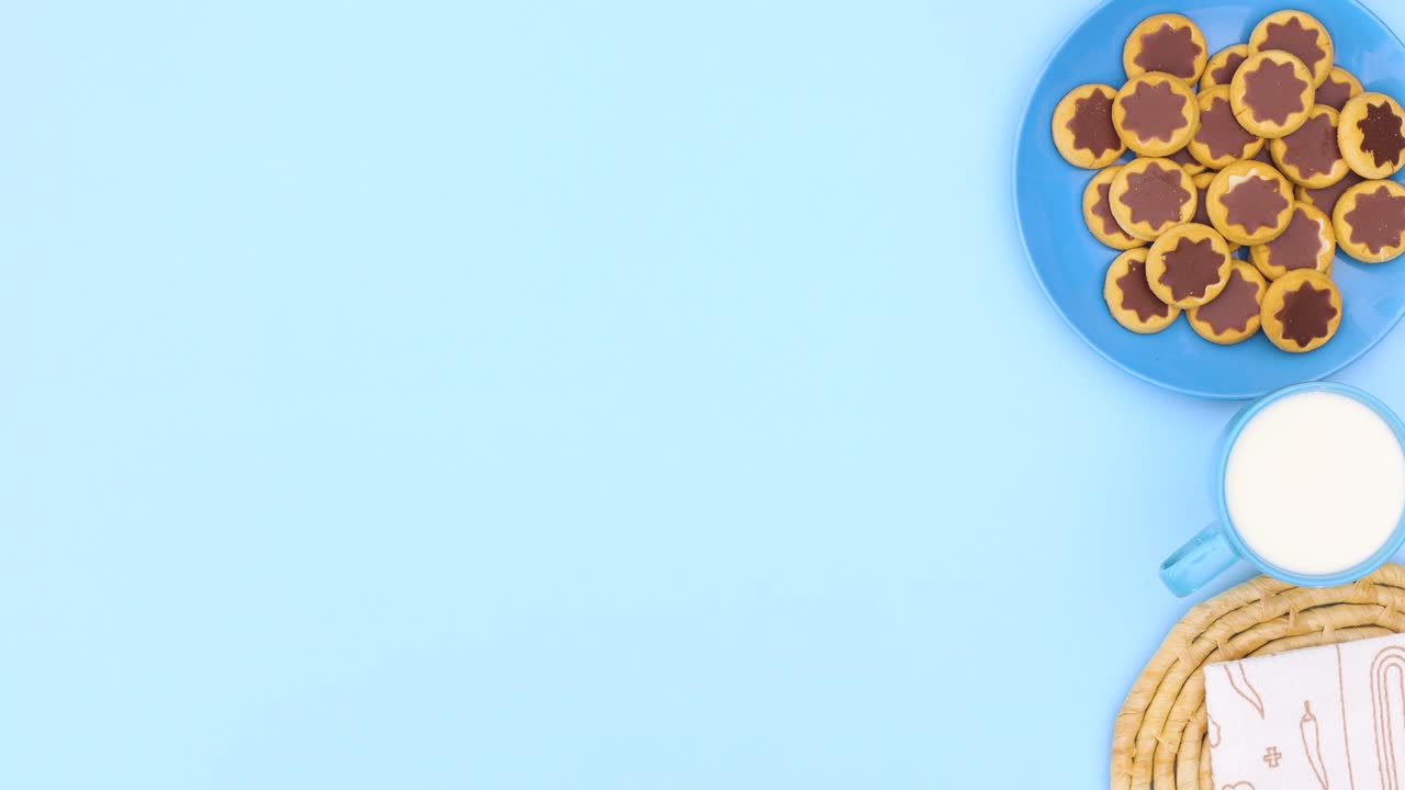 el marco blanco para la receta aparece en el tema azul con galletas en el plato azul y una taza de leche en el lado derecho. detener el movimiento