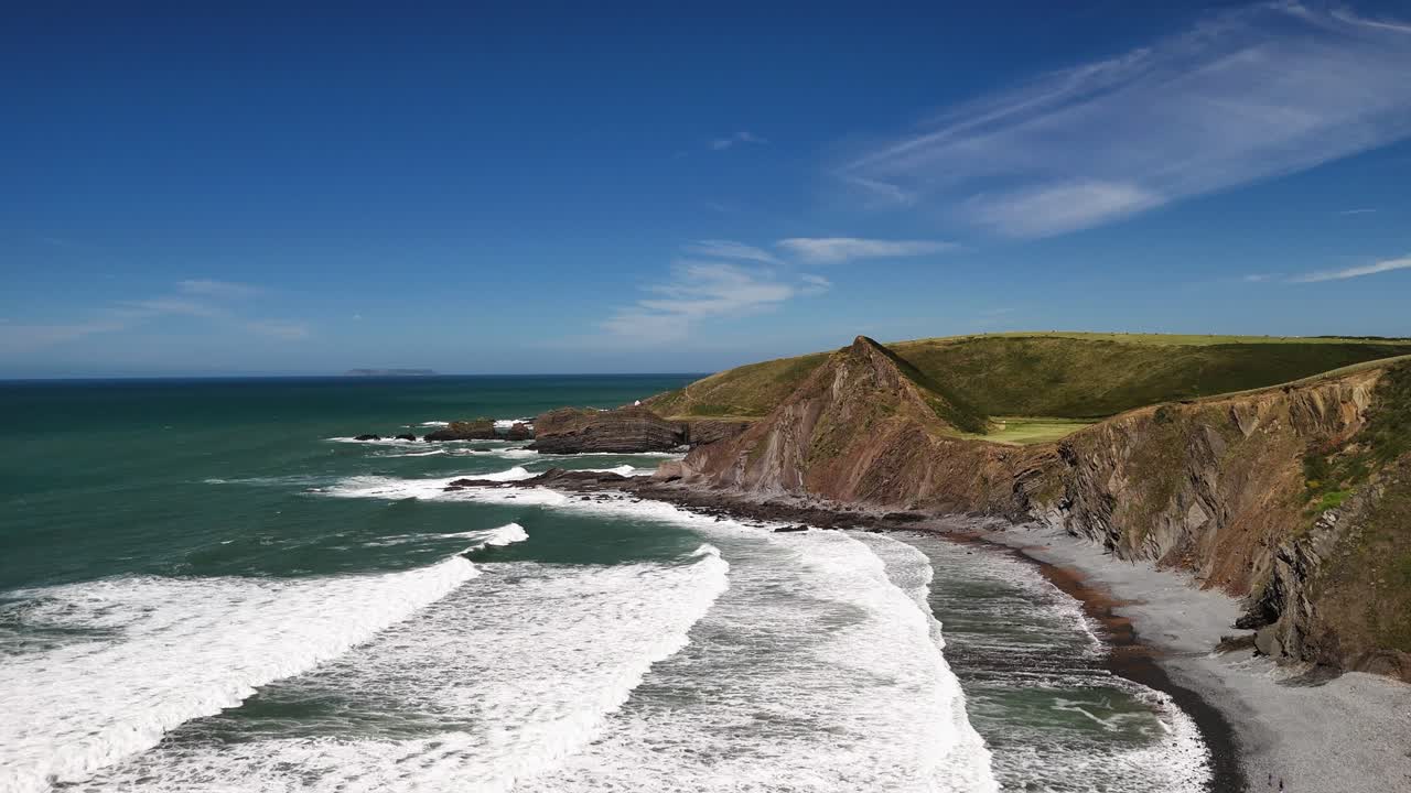 Dramatic aerial shot flying over a cliff and revealing a secluded wild beach