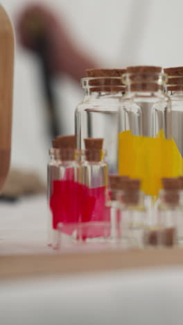 glass bottles of different sizes with corks stand on table in white tent. sorceress prepares containers for magic potion on blurred background