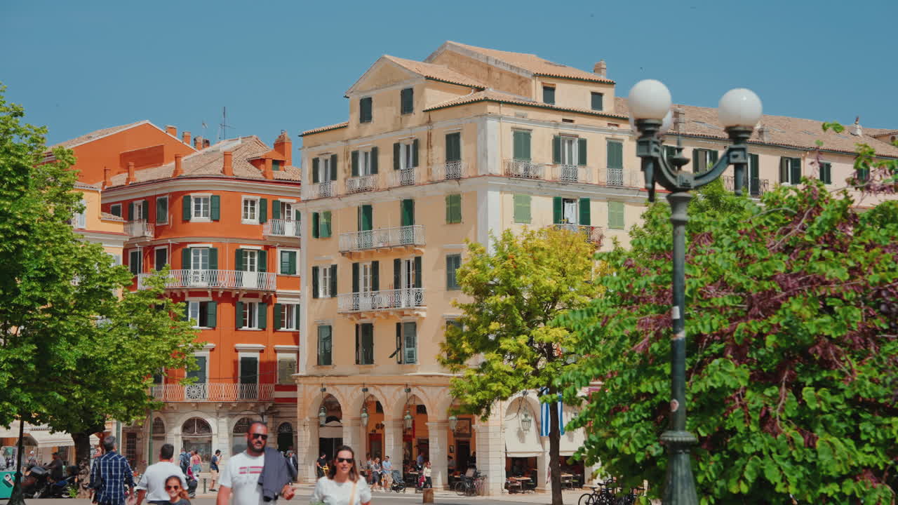 People walking in a bustling European town square with historic buildings and trees