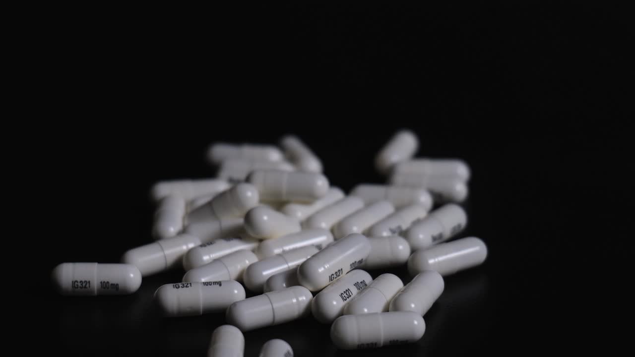 Pillole su prescrizione che fuoriescono da una bottiglia su uno sfondo scuro