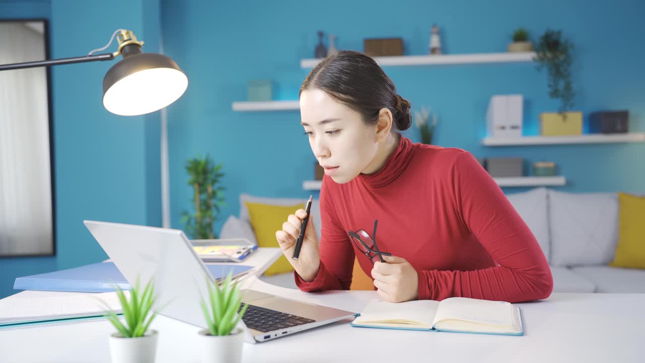 아시아 여자가 노트북에 본 것을 쓰고 있습니다.