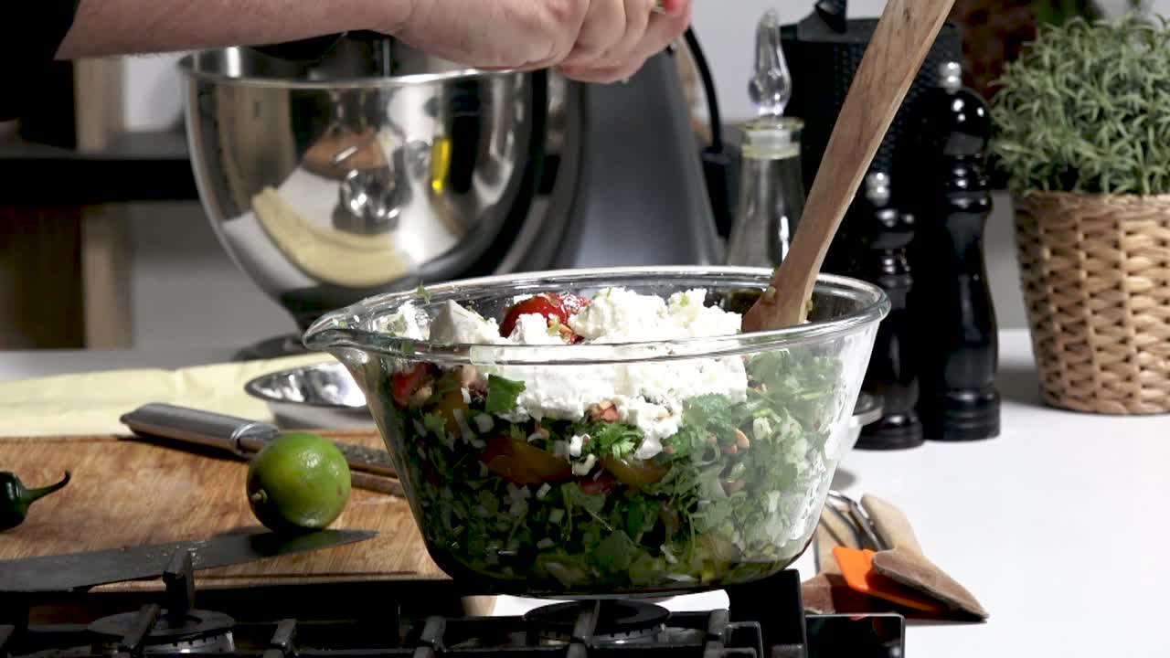 Squeeze out the juice of lime and sprinkle the lime juice over the vegetable salad. The cook prepares a salad of tomatoes, parsley, and white cheese, seasoning the chopped vegetables with lime juice