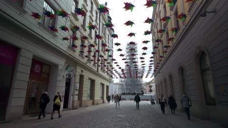 decoration of olomoucká street with windmills. people walking through the city. in the background, the repair of the column of the holy trinity. czech republic