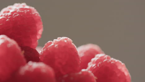 Micro video of close up of raspberries with copy space on grey background