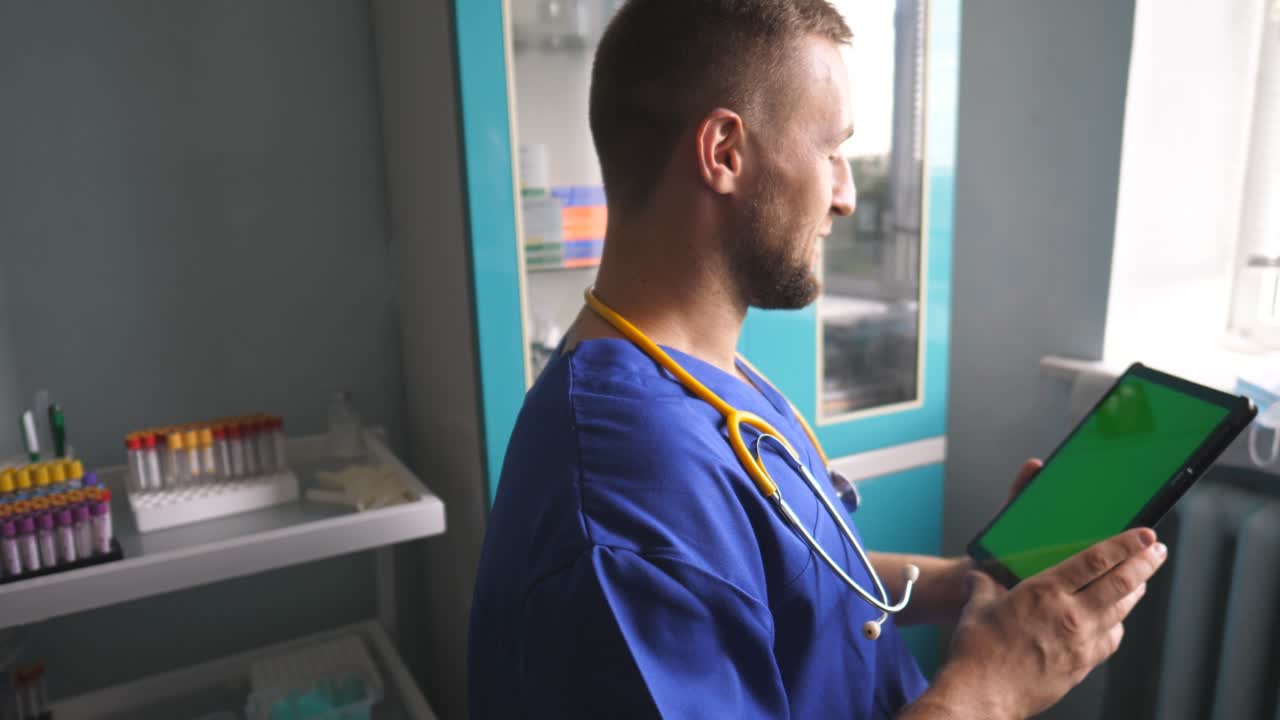 Mandlig læge taler med en person, der bruger en tablet. Sundhedspersonale rådgiver patienter via en digital enhed. Læge arbejder i et laboratorium under coronapandemien. Koncept for sundhed og moderne teknologi