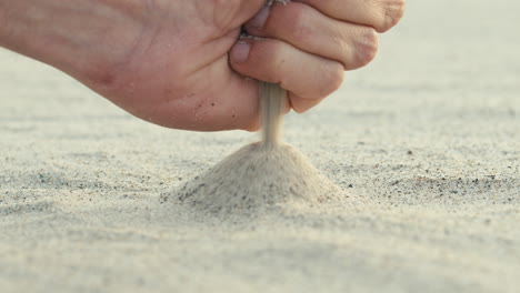 hand playing with sand on the summer beach