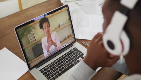 Afroamerikanischer-Männlicher-College-Student,-Der-Notizen-Hält,-Während-Er-Zu-Hause-Einen-Videoanruf-Auf-Dem-Laptop-Führt