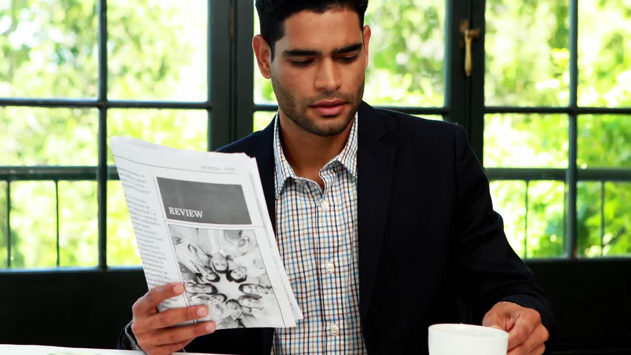 Empresário lendo jornal enquanto toma café 4k