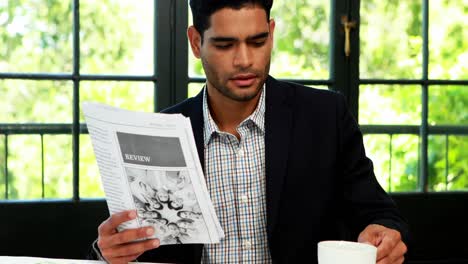 Businessman-reading-newspaper-while-having-coffee-4k