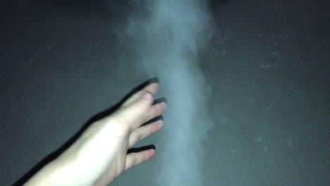 a female hand catches a jet of white steam and plays with it