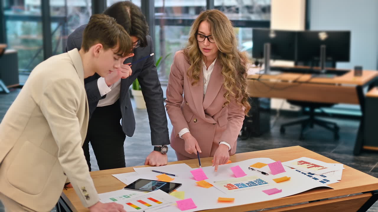 Business meeting in an office, female team leader and two young workers discussing business affairs using papers. Slow motion