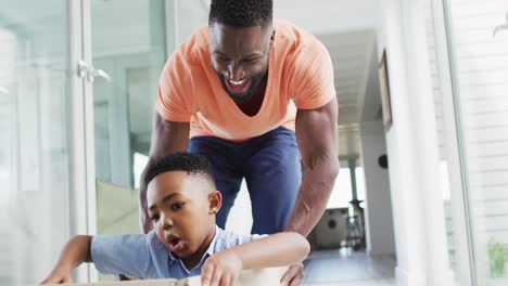 African-american-father-and-son-playing-with-a-cardboard-box-in-a-hallway