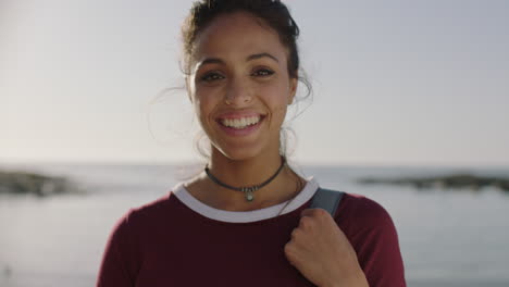 close-up-portrait-of-beautiful-hispanic-woman-smiling-happy-on-sunny-beach-holding-backpack