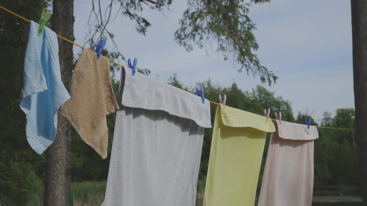 Big And Small Towels Hanging On The Clothesline With Clothes Pin For Drying On A Hot Windy Day - close up slowmo