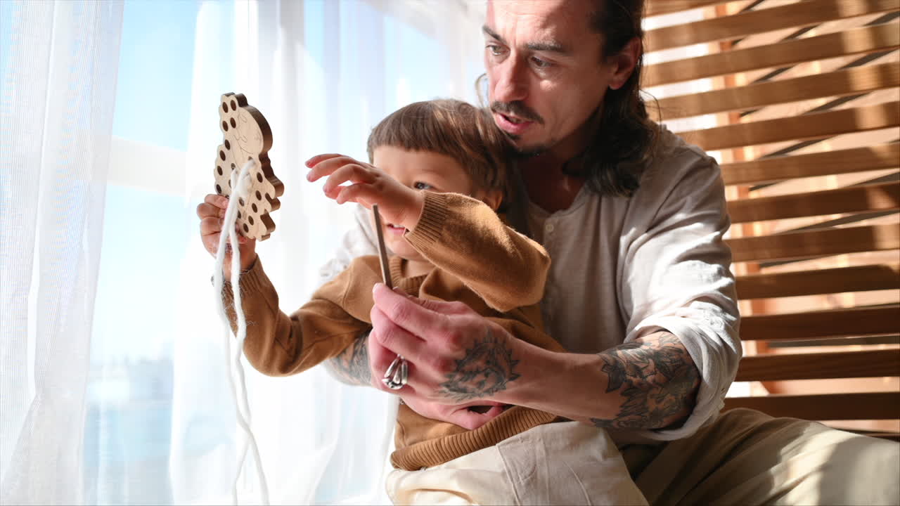 Father playing with his son with ecological wooden toys near the window