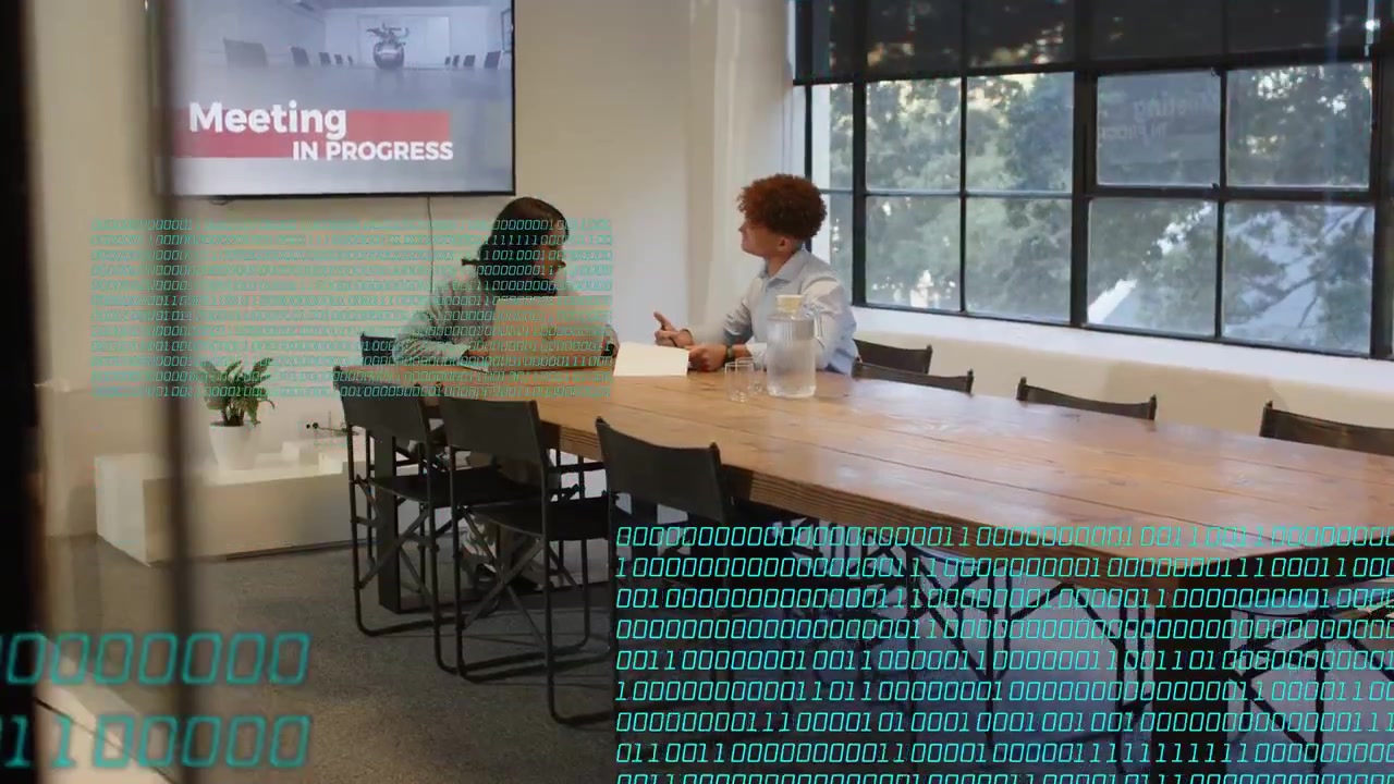 Two coworkers leaning in, reviewing paper, passing pen, causing turquoise code overlay for business
