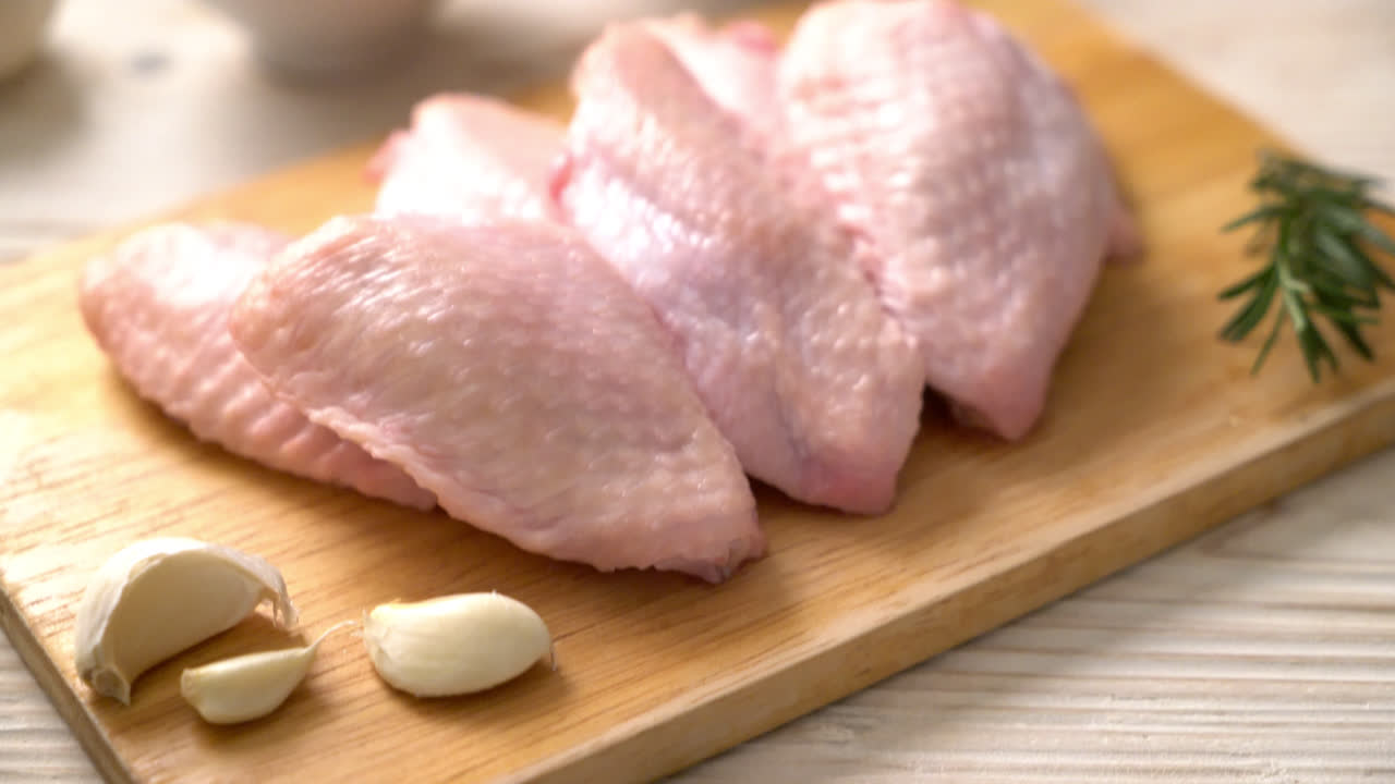 ali di pollo medie fresche crude su tavola di legno con ingredienti