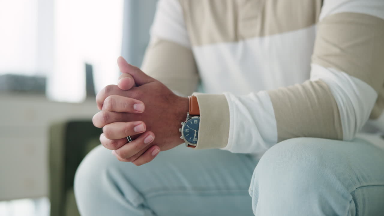 Man sitting with hands clasped wearing a watch