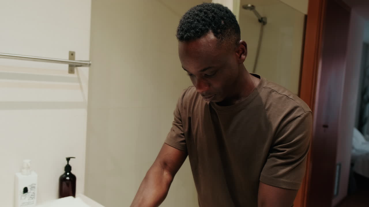 Young African Man Checking His Face in Bathroom Mirror