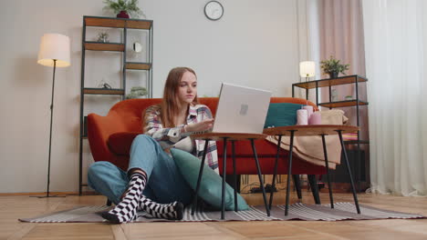 cheerful young woman sitting on floor, using laptop pc share messages on social media application