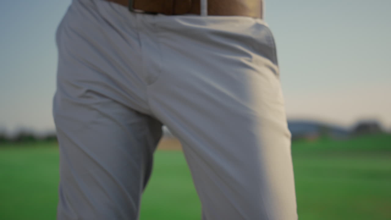 남자가 선 ⁇  컨트리 클럽에서 골프를 치고 있습니다. 골퍼가 파터를 사용하여 공을 때리고 있습니다.